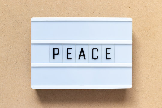 White lightbox with word peace on wood background