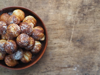 Homemade baking donuts. Deep-fried, in vegetable oil in a frying pan. Holiday and everyday food. Place for text. Brown wooden background.