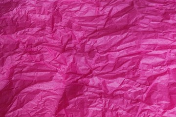 Crumpled pink magenta tissue paper for background or gift wrapping. Abstract textured wrinkled crimson parchment backdrop.Surface of fuchsia color wrapping paper with creases texture for background.
