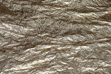 Abstract textured wrinkled tin foil background.Crumpled foil paper texture for background.Surface of crumpled  foil with a hint of silver and gold for backdrop.