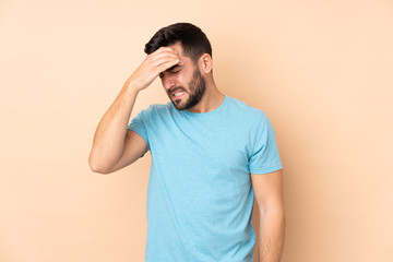 Caucasian handsome man isolated on beige background with headache