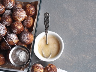 Homemade baked donuts on a gray background in a glass form for the oven with a strainer with icing sugar.