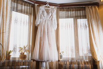 The bride's dress hangs on the window.