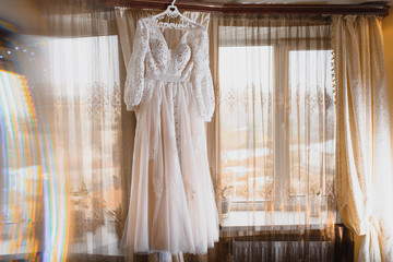 The bride's dress hangs on the window.