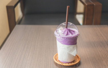 Iced blueberry smoothie cup on wood table in coffee shop