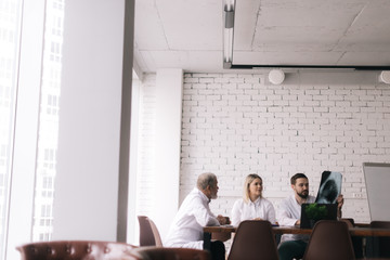 Medical team of three adult and young doctors discuss chest X-rays in the conference room of the hospital. Concept of team of doctors working together at the clinic. Concept of team medical work.