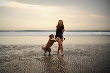 Girl playing with her cute dog on the sea coast