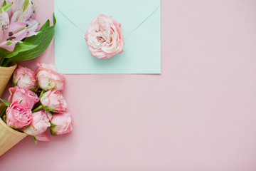 Ice cream cones with pink flowers and mint envelope on pink pastel background