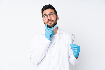 Dentist man holding tools isolated on white background thinking an idea