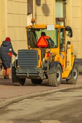 Mini excavator for cleaning city streets on the sidewalk.