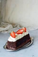 Chocolate brownie with airy vanilla cream and fresh strawberries. Chocolate cake with cream and fresh berries. Tea dessert