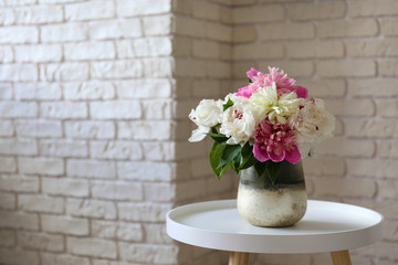 Empty apartment with minimal loft style interior, wooden floor and glass vase with bouquet of peonies on foreground and blank wall with a lot of copy space for text on background. Close up.