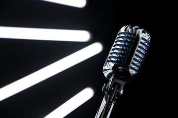close up of microphone in Music Studio with Black walls and lights at background