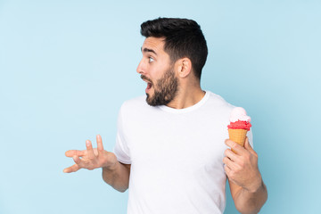 Caucasian man with a cornet ice cream isolated on blue background with surprise facial expression