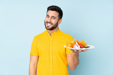Caucasian man holding waffles isolated on blue background