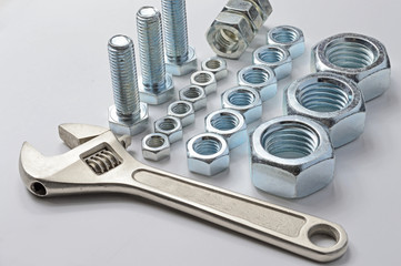 new bolts and nuts of different sizes and adjustable spanners arranged in rows on a white background.