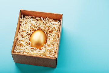 Golden egg in a box on a blue background Concept of exclusivity, best choice, prize, special surprise, expensive gift.