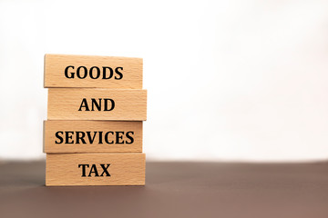 Goods and services and tax . GST inscription in Notepad on wooden block on white background