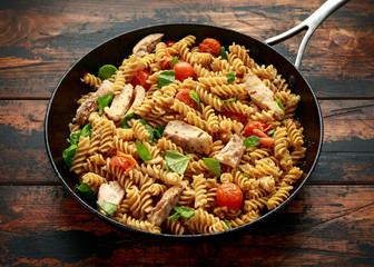 Healthy Chicken, fusilli pasta with tomatoes, basil and parmesan cheese in iron pan.