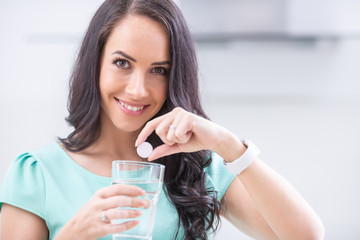 Young woman with magnesia effervescent tablet and glass of pure or mineral water - obrazy, fototapety, plakaty