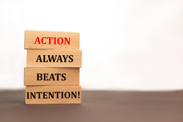 wooden block with text Action Always Beats Intention on white background
