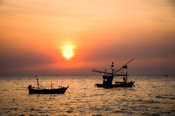 A local fishing boat in the eastern part of Thailand is parked in the sea with a backdrop of sunset.