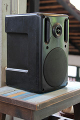 Black plastic sound speaker on wooden table.