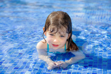Fototapeta na wymiar portrait of a pretty little girl playing in a swimming pool