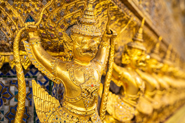 The Golden Garuda and Naga Statue Decorated with colored glass On the wall of the Buddhist temple at Emerald Buddha Temple And the royal palace Bangkok, Thailand