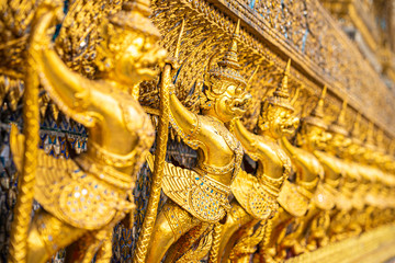 The Golden Garuda and Naga Statue Decorated with colored glass On the wall of the Buddhist temple at Emerald Buddha Temple And the royal palace Bangkok, Thailand