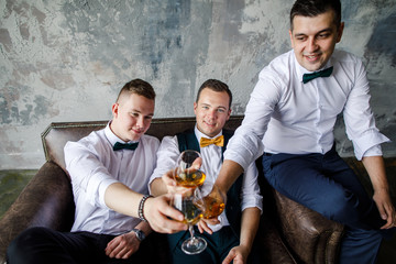 three men in a white shirt drink whiskey in glasses in a loft apartment
