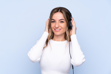 Naklejka premium Young woman over isolated blue background listening music