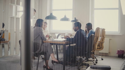 Dolly shot of teamwork at loft modern office table. Multiethnic business people cooperate, discuss market at meeting 4K.