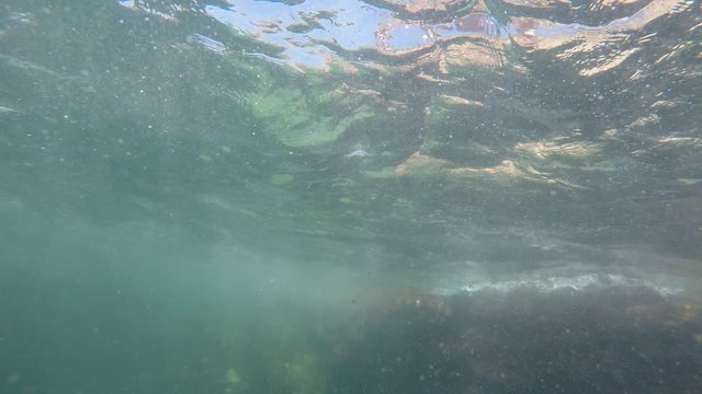 Caucasian girl doing flips and dives into sea water. View from under water