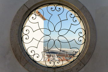 Round window with a black metal fence and a pattern in an old stone facade with a view to the sky