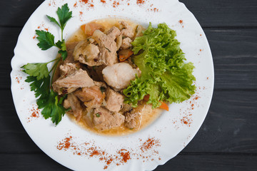 Plate of grilled beef nuggets, fried potato chips or French fries and fresh leafy green salad with cucumber on a white background
