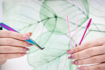 tools for eyelash extensions in hands on a background with a natural pattern