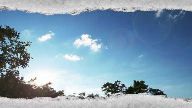 Creative time laps video of fast moving clouds in the blue sky at sunset witn sunflare that are visible through a hole with torn edges in old retro grunge vintage paper.