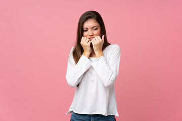 Young woman over isolated pink background nervous and scared putting hands to mouth