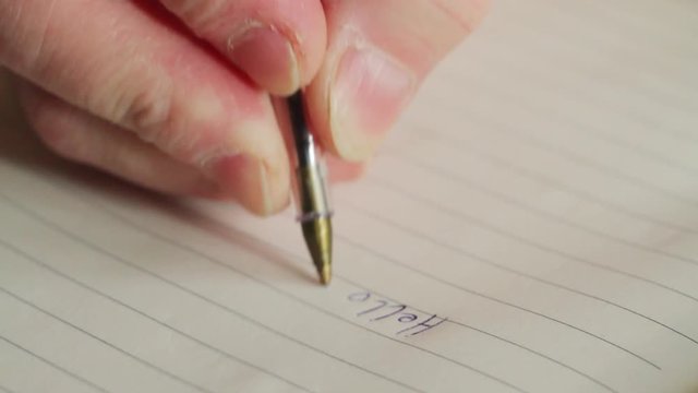 a man writes with a pen in a notebook a letter to his mother: Hello mom. extreme close-up, no sound, Full HD,