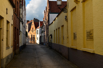 Fototapeta premium Bruges, Belgium. August 2019. In the small secondary streets of the center the late afternoon sun illuminates the brick facades of the typical houses. Nobody.