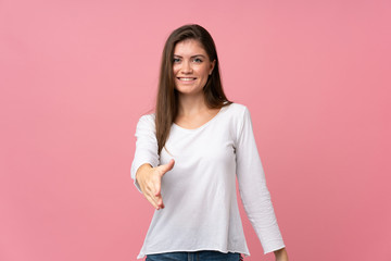 Young woman over isolated pink background shaking hands for closing a good deal