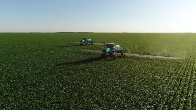 Agriculture, beautiful aerial image of machines spraying soybean plantation in the open field with circular motion - Agribusiness.