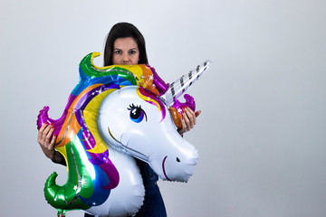 Simbolo de victoriapretty caucasian middle age woman with unicorn balloon making victory or peace sign, isolated on gray background studio shotblack sweater, denim jacket, jeans, dark air. Place for y