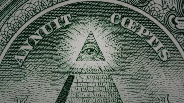 Creative 4k video of details of a 1 american dollar banknote macro closeup with a pyramid and the effect of a glowing mason eye on top. Pyramid close-up on a banknote of 1 US dollars.