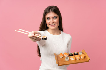 Young girl with sushi over isolated pink background