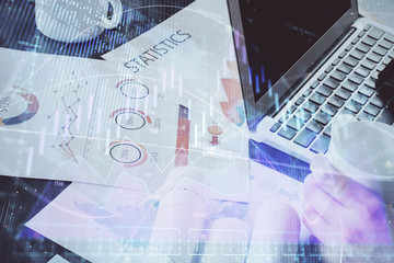 Double exposure of stock graph with businessman typing on computer in office on background. Concept of hard work.