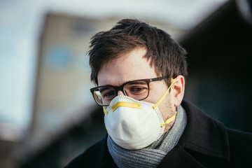 Flue and corona safety concept. Man wearing face mask to protect himself, outdoors.