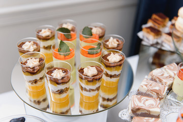 desserts with fruits, mousse, biscuits. Different types of sweet pastries, small colorful sweet cakes, macaron, and other desserts in the sweet buffet. candy bar for birthday