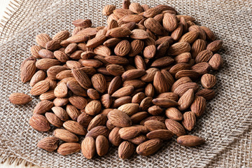 Closeup almonds nut are  on sack and wooden table.